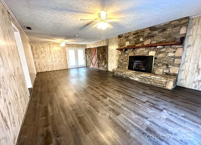 unfurnished living room featuring a ceiling fan, a textured ceiling, visible vents, and dark wood-type flooring