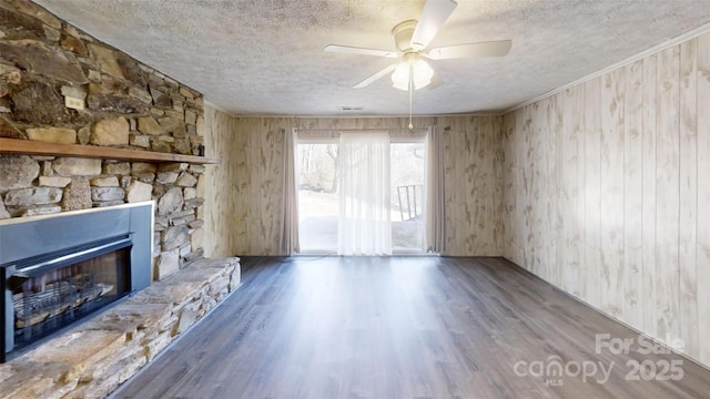 unfurnished living room with a fireplace, a textured ceiling, and wood finished floors