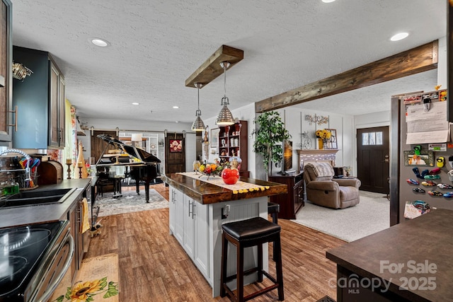 kitchen with a kitchen island, a breakfast bar, decorative light fixtures, sink, and white cabinets