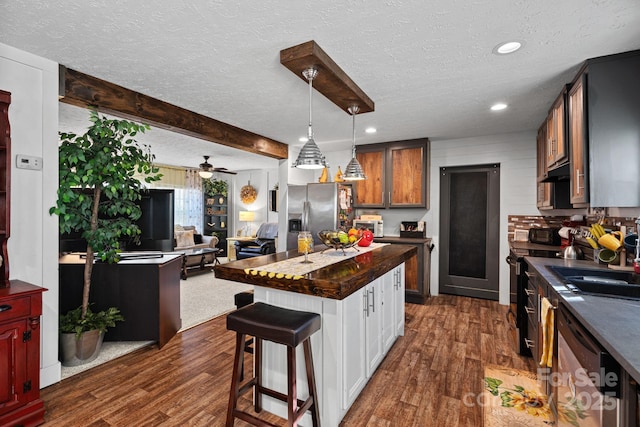 kitchen with appliances with stainless steel finishes, dark hardwood / wood-style flooring, a center island, and a breakfast bar area