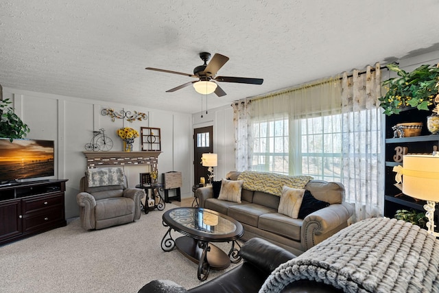 living room with ceiling fan, carpet floors, and a textured ceiling