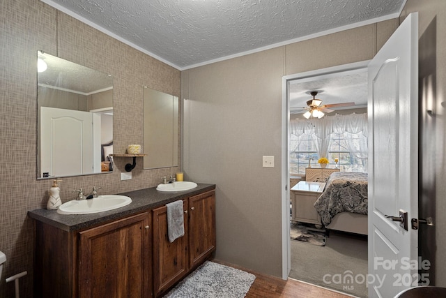 bathroom with ceiling fan, vanity, ornamental molding, a textured ceiling, and decorative backsplash