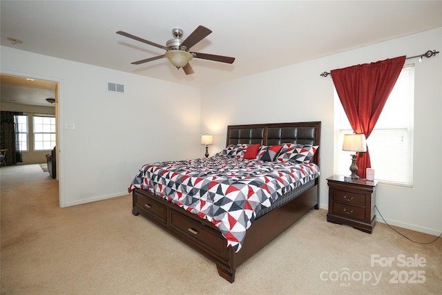 bedroom featuring ceiling fan, light colored carpet, and multiple windows