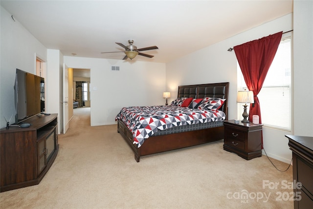 bedroom featuring light carpet, ceiling fan, and multiple windows