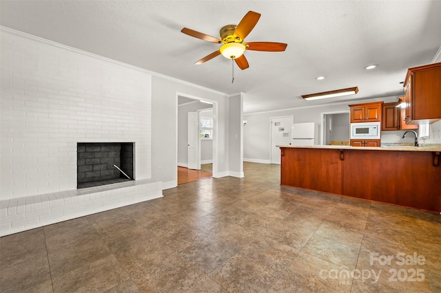 kitchen featuring white appliances, ceiling fan, kitchen peninsula, a brick fireplace, and crown molding