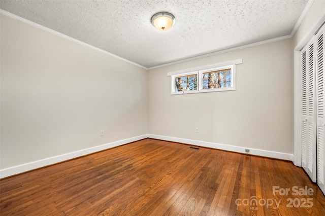 unfurnished bedroom with a closet, ornamental molding, a textured ceiling, and hardwood / wood-style floors