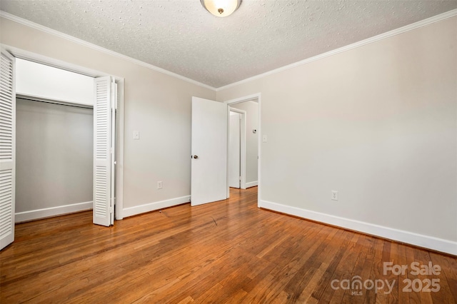 unfurnished bedroom featuring a textured ceiling, a closet, crown molding, and hardwood / wood-style floors