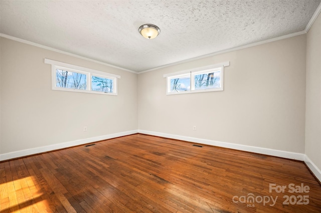 empty room with a textured ceiling, a wealth of natural light, crown molding, and wood-type flooring