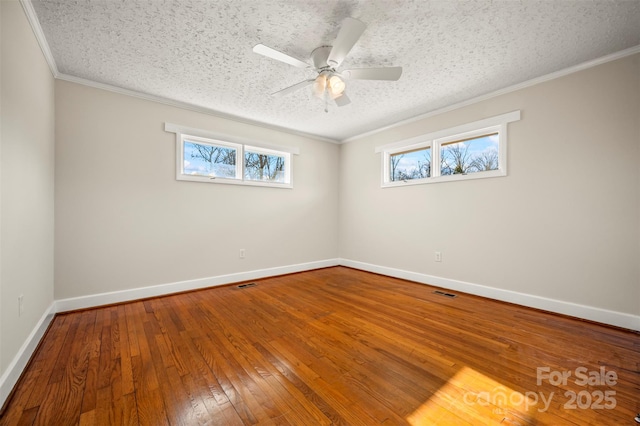 empty room with ceiling fan, a wealth of natural light, ornamental molding, and hardwood / wood-style floors