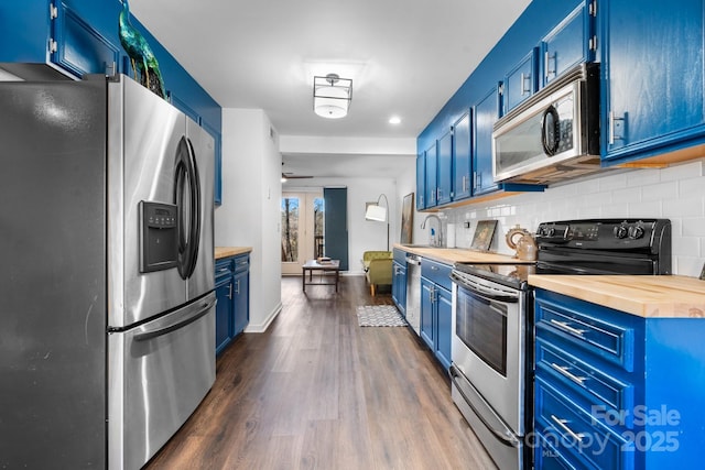 kitchen with blue cabinetry, wooden counters, backsplash, stainless steel appliances, and dark hardwood / wood-style floors