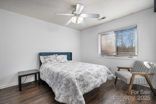 bedroom with ceiling fan, a textured ceiling, and dark hardwood / wood-style floors