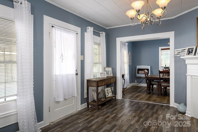 foyer with an inviting chandelier, dark wood-type flooring, heating unit, a fireplace, and crown molding