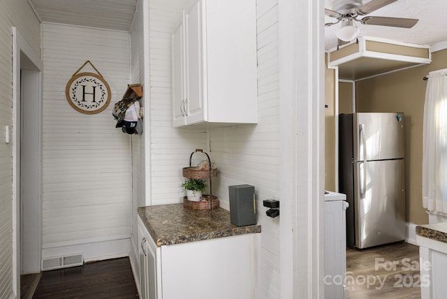 kitchen with dark wood-type flooring, ceiling fan, stainless steel fridge, and white cabinetry