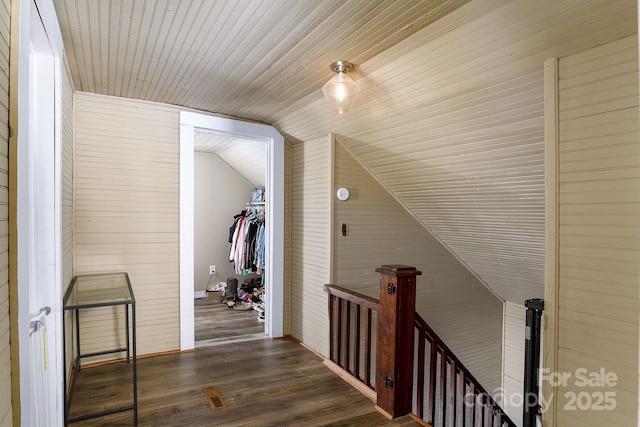 hallway with lofted ceiling, dark hardwood / wood-style flooring, wood ceiling, and wood walls