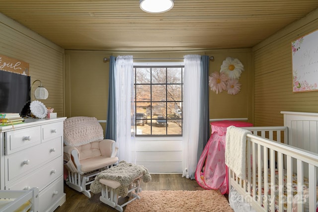 bedroom featuring dark wood-type flooring, wood ceiling, and a crib