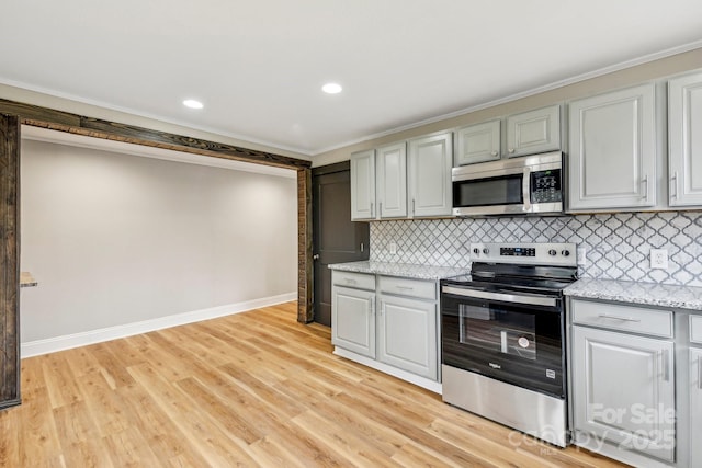 kitchen featuring appliances with stainless steel finishes, light stone countertops, decorative backsplash, and light wood-type flooring