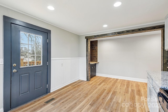 entrance foyer featuring ornamental molding and light wood-type flooring