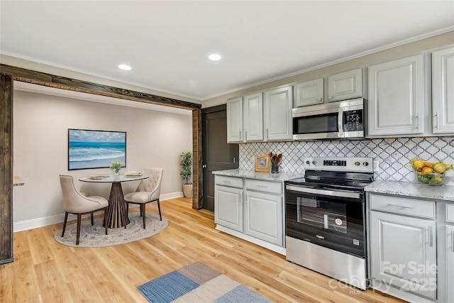 kitchen with appliances with stainless steel finishes, tasteful backsplash, light hardwood / wood-style floors, crown molding, and light stone countertops