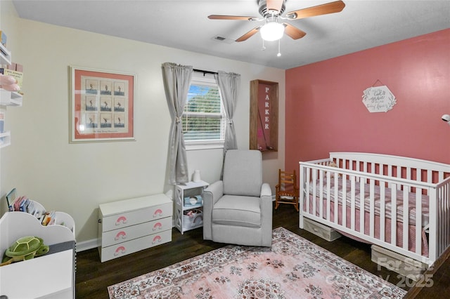 bedroom with ceiling fan, dark hardwood / wood-style flooring, and a crib