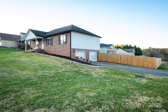 view of side of home featuring a garage and a lawn