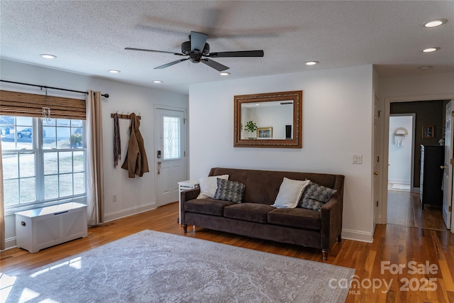 living room with ceiling fan, wood-type flooring, and a textured ceiling