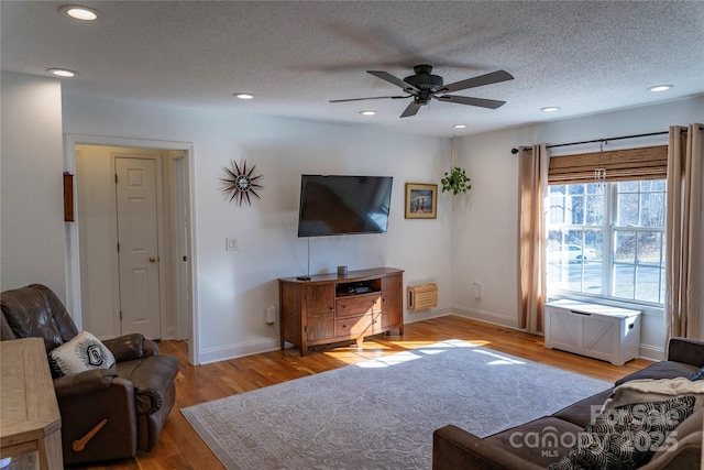 living room with ceiling fan, light hardwood / wood-style floors, and a textured ceiling