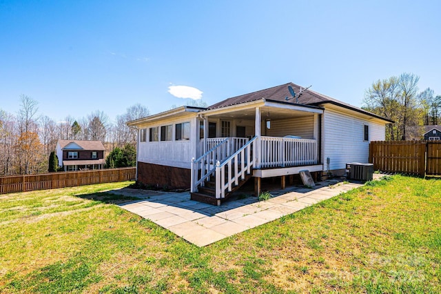 back of property with a yard, a porch, and fence