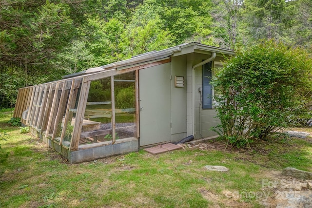 view of outdoor structure with a lawn and a sunroom