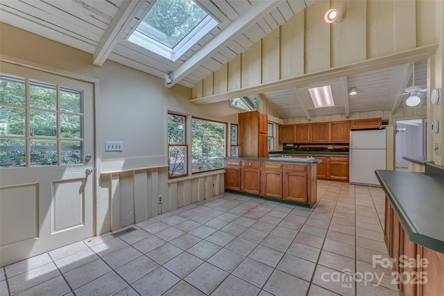 kitchen with white fridge, a wealth of natural light, light tile patterned floors, and lofted ceiling with skylight