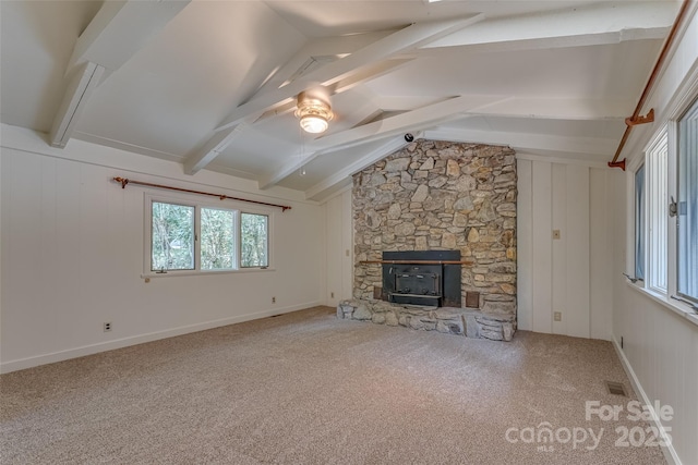 unfurnished living room with ceiling fan, a wood stove, carpet floors, and lofted ceiling with beams