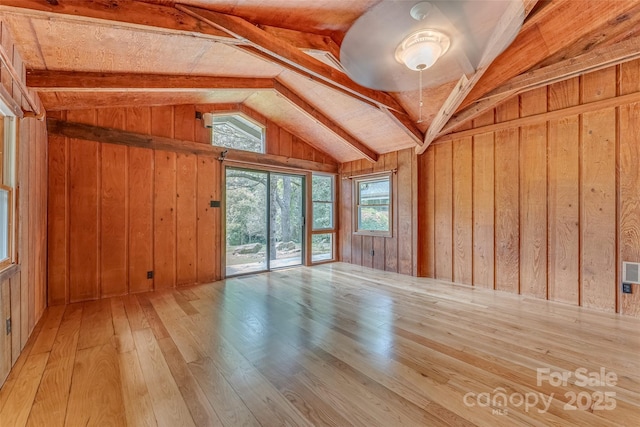 interior space featuring light hardwood / wood-style floors, wood walls, and vaulted ceiling with beams