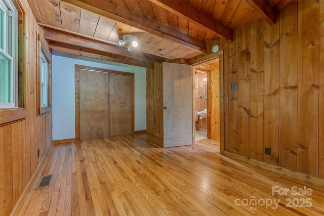 unfurnished bedroom featuring wooden ceiling, light hardwood / wood-style flooring, wood walls, and beamed ceiling