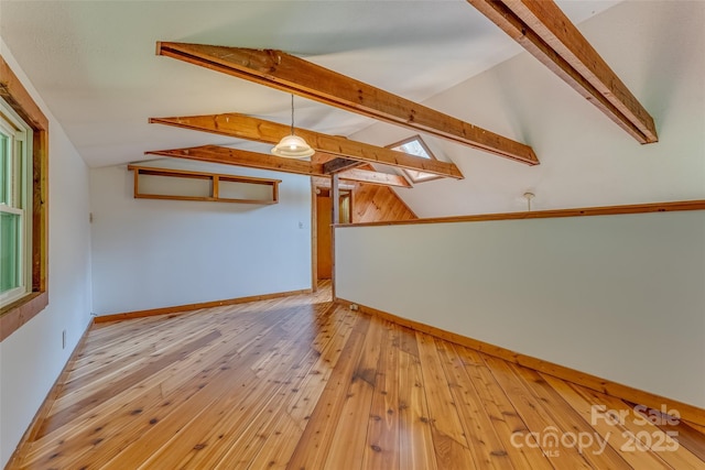 interior space featuring light wood-type flooring and vaulted ceiling with beams