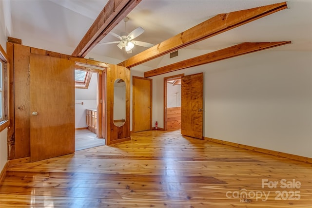 unfurnished room with ceiling fan, lofted ceiling with skylight, and light hardwood / wood-style flooring