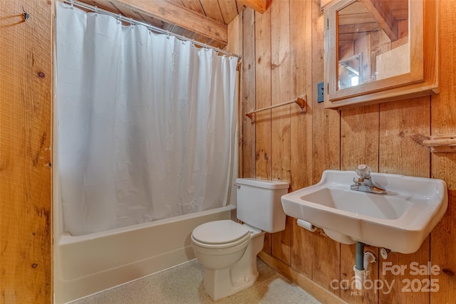 full bathroom featuring shower / bath combo with shower curtain, toilet, and wooden walls