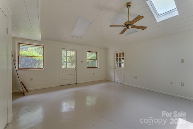 unfurnished room with ceiling fan, a wealth of natural light, and vaulted ceiling with skylight