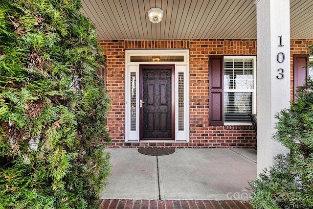 property entrance with covered porch and brick siding