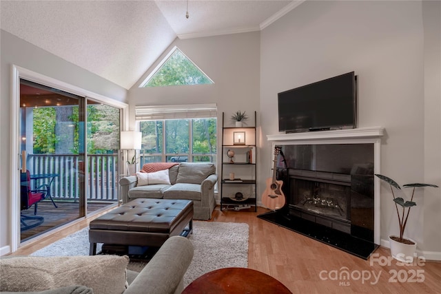 living room with a tiled fireplace, a textured ceiling, wood finished floors, baseboards, and vaulted ceiling