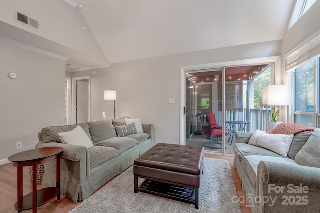 living room with visible vents, wood finished floors, crown molding, and vaulted ceiling