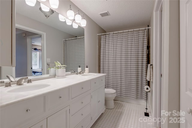 bathroom featuring tile patterned flooring, visible vents, double vanity, and a sink