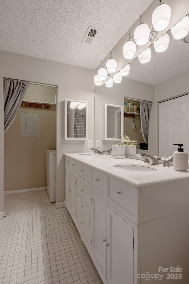 bathroom with visible vents, a sink, washer / clothes dryer, a textured ceiling, and double vanity