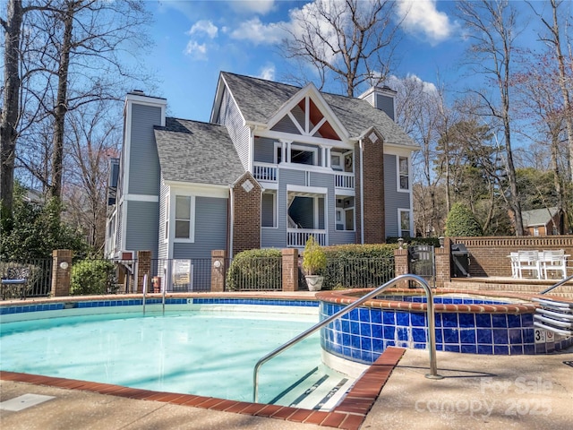 rear view of property with a community pool, a chimney, and fence