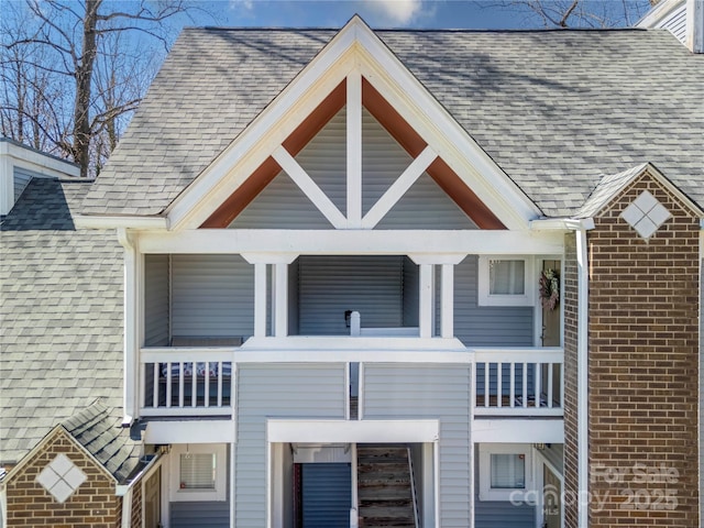 exterior space featuring brick siding and a shingled roof