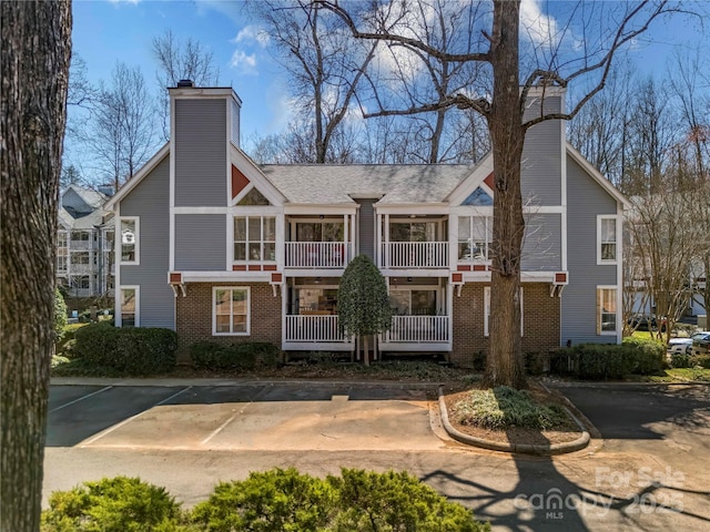 exterior space featuring uncovered parking, brick siding, and a chimney