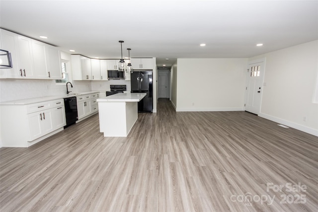 kitchen with hanging light fixtures, sink, white cabinets, a kitchen island, and black appliances