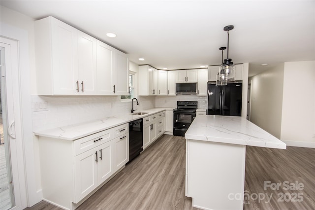 kitchen with white cabinetry, hanging light fixtures, black appliances, and a kitchen island