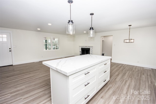 kitchen featuring hanging light fixtures, white cabinets, a center island, and light wood-type flooring