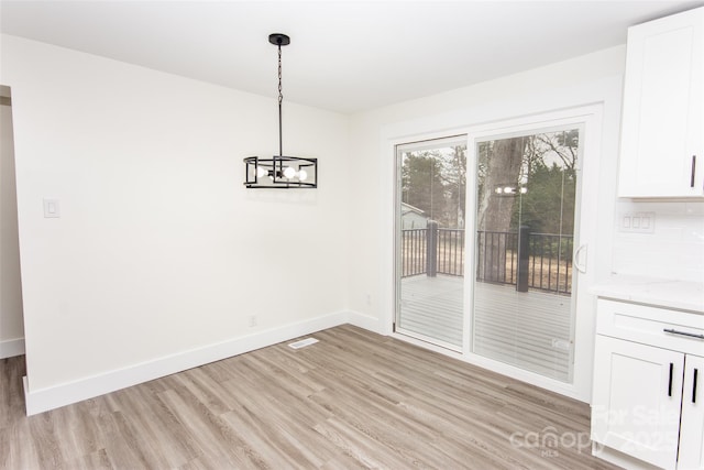 unfurnished dining area with a chandelier and light wood-type flooring