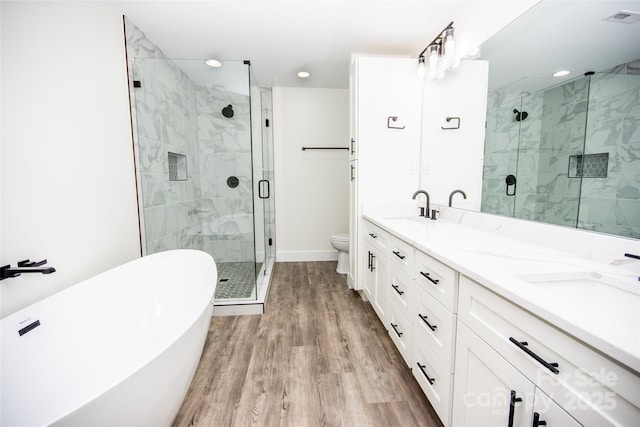 full bathroom with hardwood / wood-style floors, independent shower and bath, toilet, and vanity