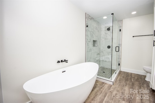 bathroom featuring hardwood / wood-style floors, plus walk in shower, and toilet